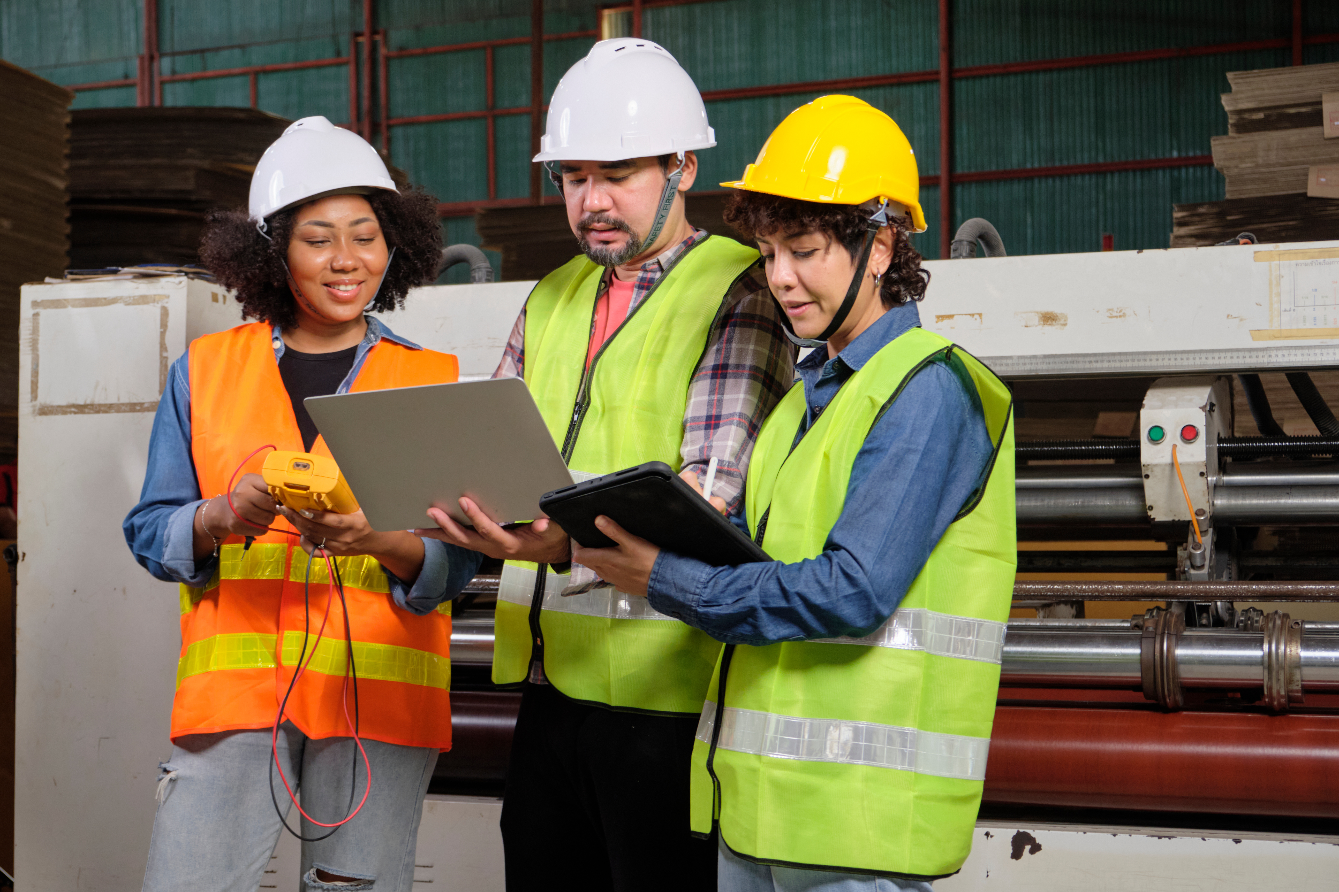 Three construction workers wearing safety vests and hard hats looking at a drawing